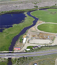 Monitoring station is to the left of red barn downstream from I-15 South bridges.